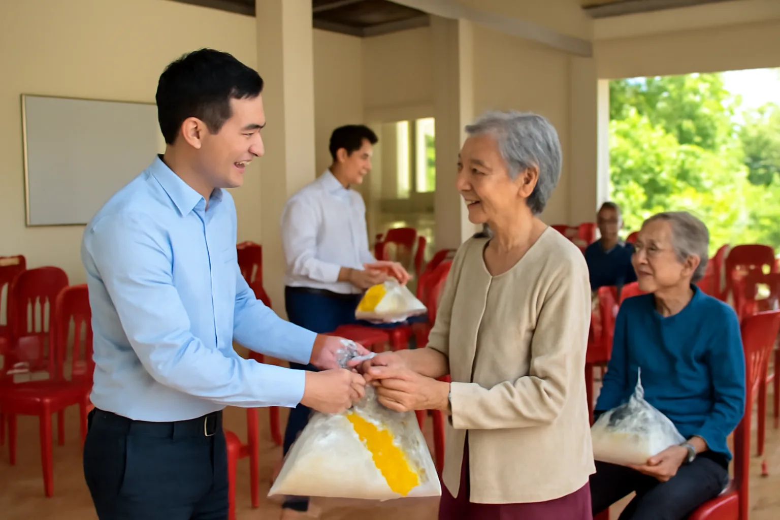 Nhân viên doanh nghiệp trao túi quà Tết cho cụ bà tại nhà văn hoá thôn